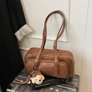 Vintage brown leather shoulder bag with bear charm on a silver suitcase setup