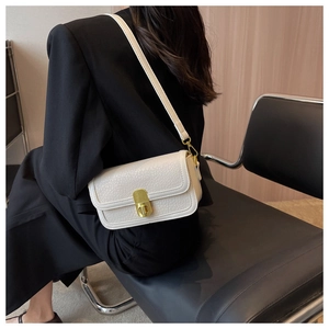 Detail of white lychee leather square bag featuring a gold cylindrical twist lock