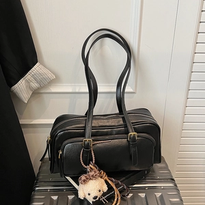 Minimalist black leather underarm bag with a cute puppy pendant on a silver suitcase