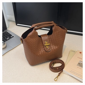 Detail of dark brown woven shoulder bag with gold metal twist lock and top handle