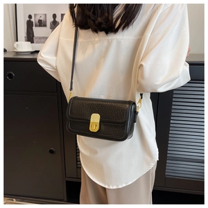 Close-up of black textured leather crossbody bag featuring a classic gold metal lock