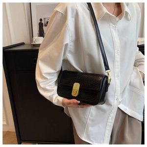 Macro detail of black litchi grain leather flap bag with elegant gold cylinder lock