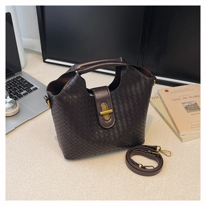 Detail of dark brown woven texture handbag with metal rotary buckle and top handle