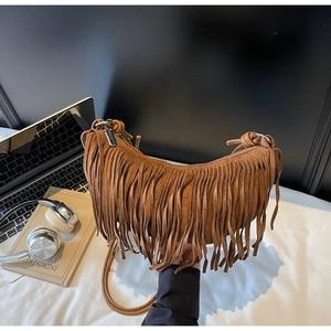Detail of a brown suede crescent bag featuring long decorative tassels and a silver zipper