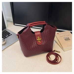 Close-up of wine red woven leather handbag with gold clasp and adjustable strap
