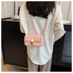 Fashionable pale pink square bag shown on shoulder in a minimalist indoor setting