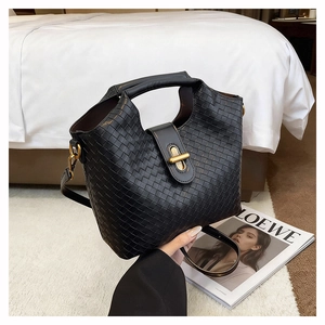 Detail of black woven leather shoulder bag showing intricate texture and gold clasp