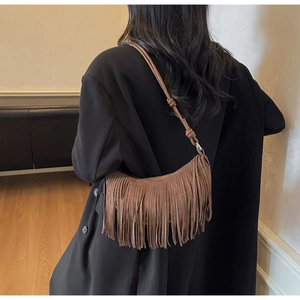 Detail of suede crescent bag showing long tassel fringe and decorative knot strap detail