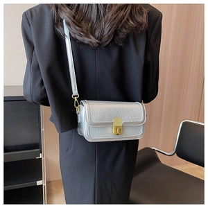 Detail of silver textured leather crossbody bag with a gold twist-lock on a black blazer