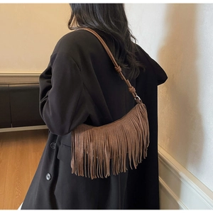 Detail of a brown suede crescent bag featuring long fringes and knotted shoulder strap