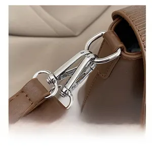Detailaufnahme des silbernen Metallhakens und sauberer Nähte einer braunen Ledertasche