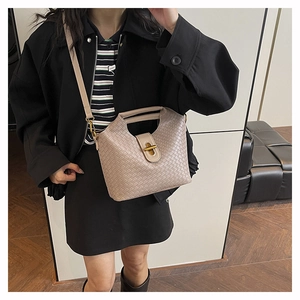 Dettaglio della trama a rombi intrecciata e chiusura a girello dorata su borsa beige
