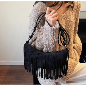 Detail showing retro black suede crescent bag with long tassels and knotted straps