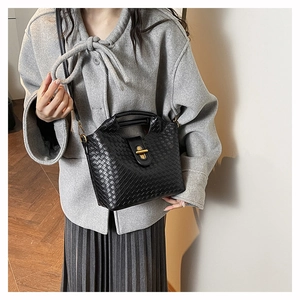 Detailed view of black woven texture and golden metal twist-lock clasp on a chic handbag