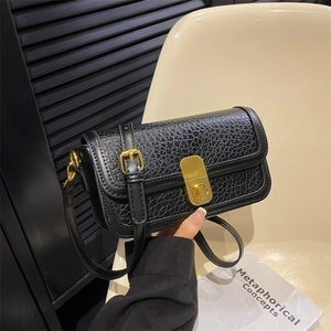 Detail of black textured leather crossbody bag with elegant gold metal twist lock
