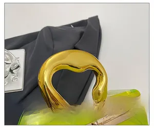 Detail of green marble acrylic evening bag featuring a unique gold metal handle