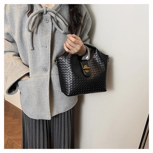 Close-up of black woven shoulder bag with golden metallic clasp and retro texture