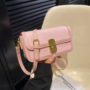 Detail of pink lychee grain leather crossbody bag with golden rectangular turn-lock