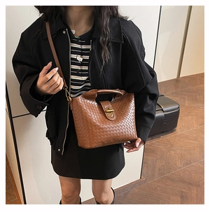 Detail of brown woven leather texture and vintage gold metal clasp on crossbody bag