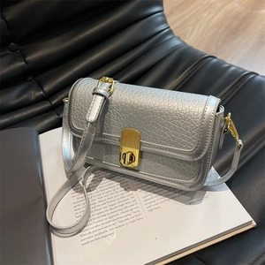 Close-up of silver litchi grain leather bag with a golden turn-lock on a magazine