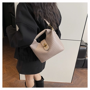 Detail of woven leather texture and golden twist lock on a beige retro crossbody bag