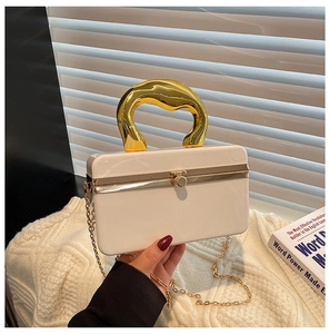 Macro detail of acrylic evening bag with gold wave handle and metal chain strap