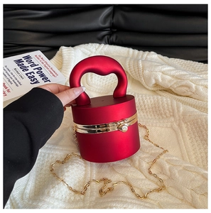 Detail of red cylindrical hard shell mini bag with gold hardware and top handle