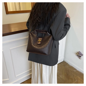 Detailed view of dark brown woven leather handbag with vintage gold metal twist lock closure