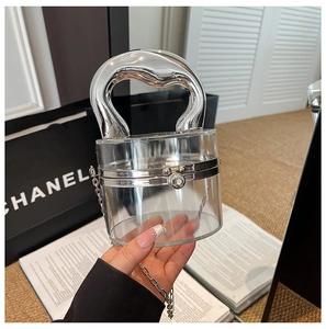 Detail of transparent acrylic cylinder bag with a sleek silver metallic handle and chain