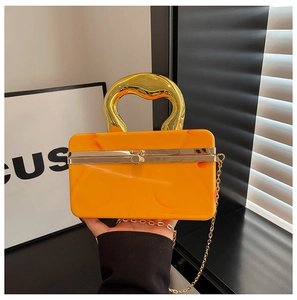 Macro detail of marble-patterned orange clutch with artistic gold handle and metal chain