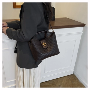Detailed close-up of dark brown woven texture with elegant gold metal buckle on handbag