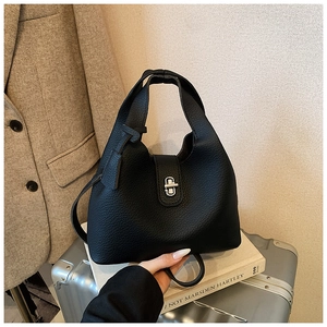 Detail of black lychee grain leather bucket bag with silver twist lock and city style props