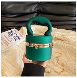 Detail of dark green cylindrical hardshell handbag with gold metal lock and chain strap