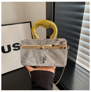 Detail showing marble-textured evening bag with a thick gold-tone abstract top handle