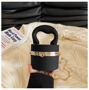Detailed shot of black mini cylinder handbag with gold ball lock and chain strap