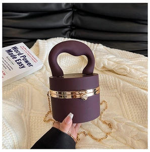 Deep purple cylindrical clutch featuring a gold chain and a heart-shaped top handle