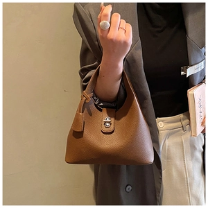 Detailed view of brown lychee grain leather bucket bag with silver twist lock and handle