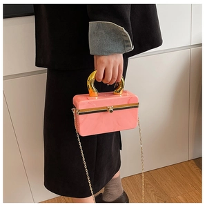 Detail of pink marble acrylic clutch bag with gold U-shaped handle and chain strap