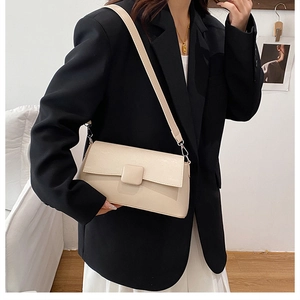 Detailansicht einer cremeweißen minimalistischen Umhängetasche an einem Model im Blazer