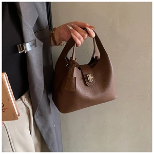 Detailed close-up of brown pebbled leather handbag with metallic turn-lock closure