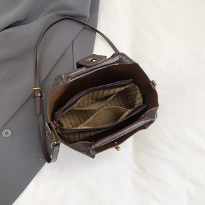 Macro view of woven shoulder bag showing multi-compartment interior and striped lining