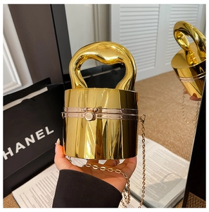 Macro view of golden mirror cylinder evening bag with wavy handle and chain strap