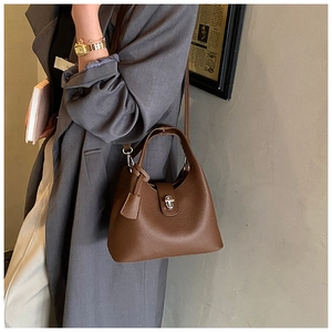 Detail of coffee brown lychee leather bucket bag with silver twist lock and strap