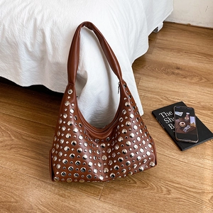 Brown retro hobo bag with silver rivets on a wide strap, styled in a casual setting