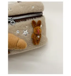 Détail du sac en peluche beige avec ferrures argentées, étoiles strass et breloque lapin