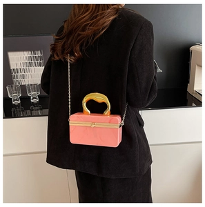 Pink marble acrylic evening bag with gold fluid handle and chain worn by a model