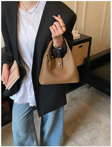 Detail of brown litchi pattern leather bucket bag with silver metal rotating lock