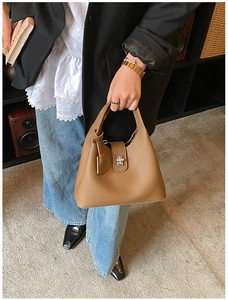 Detailed close-up of brown litchi grain leather bucket bag with silver rotating lock buckle