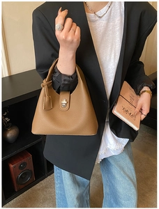 Close-up of brown lychee grain leather handbag featuring a silver metal rotating twist lock
