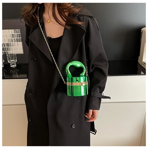 Detail of emerald green cylindrical acrylic bag with gold chain and circular handle